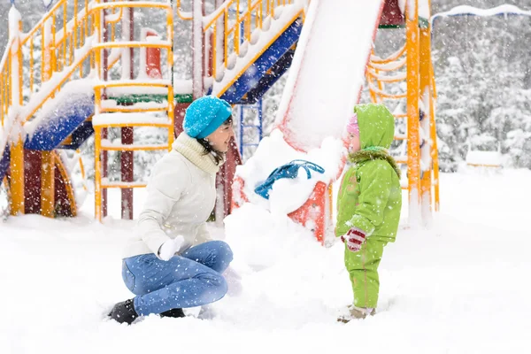 Baby und Mutter spielen mit dem ersten Schnee — Stockfoto