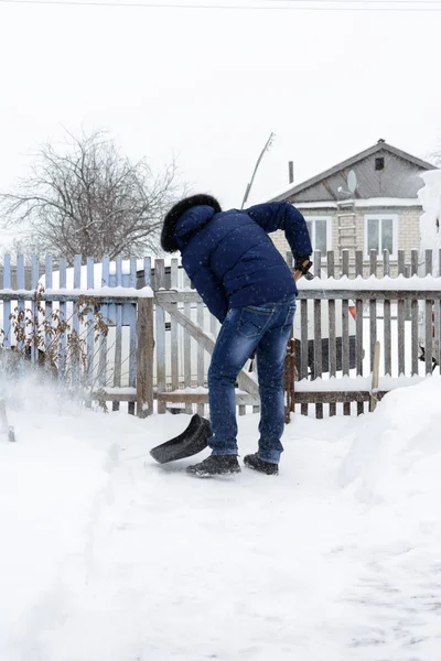 De jonge man wist sneeuw in de tuin — Stockfoto