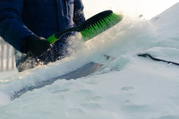 Young man cleans snow from car — Stock Photo, Image