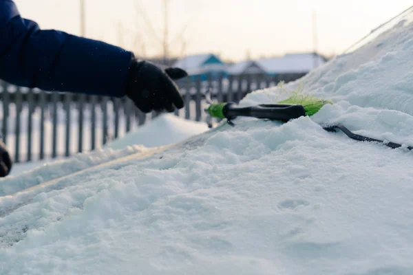 Молодой человек убирает снег из машины — стоковое фото