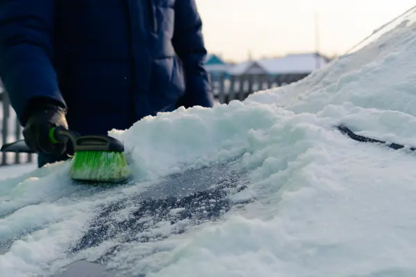 Young man cleans snow from car — Stock Photo, Image