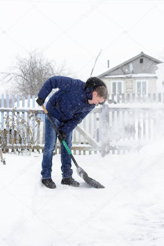 The young man clears snow in the yard