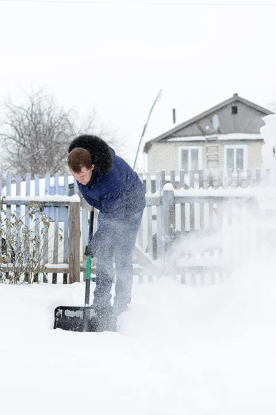 Молодой человек убирает снег во дворе — стоковое фото