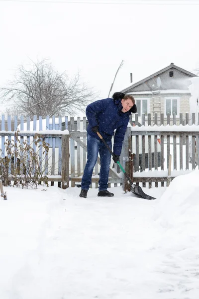 Il giovane pulisce la neve nel cortile — Foto Stock