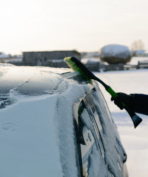 Молодой человек убирает снег из машины — стоковое фото