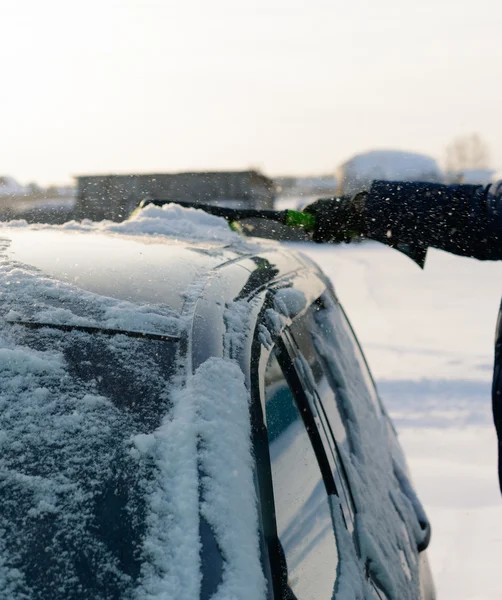 Giovane uomo pulisce la neve dalla macchina — Foto Stock