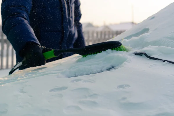 Young man cleans snow from car — Stock Photo, Image