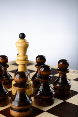 siyah piyonlar tarafından çevrili beyaz Kraliçe