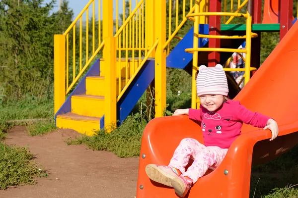 Little girl playing on the playground in summer — Stock Photo, Image