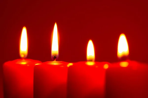 四支燃烧的蜡烛在雪暗的红色背景上 — 图库照片