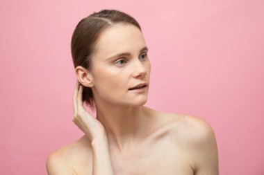 Güzel, şehvetli, üstsüz esmer kadın pembe arka planda yalnız duruyor, poz veriyor. Mutlu kadın model. İnsani duygular ve duygular. Çıplak makyaj. Spa