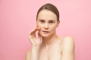 Güzel, şehvetli, üstsüz esmer kadın pembe arka planda yalnız duruyor, poz veriyor. Mutlu kadın model. İnsani duygular ve duygular. Çıplak makyaj. Spa