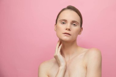 Güzel, şehvetli, üstsüz esmer kadın pembe arka planda yalnız duruyor, poz veriyor. Mutlu kadın model. İnsani duygular ve duygular. Çıplak makyaj. Spa