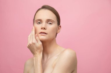 Güzel, şehvetli, üstsüz esmer kadın pembe arka planda yalnız duruyor, poz veriyor. Mutlu kadın model. İnsani duygular ve duygular. Çıplak makyaj. Spa