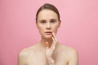 Güzel, şehvetli, üstsüz esmer kadın pembe arka planda yalnız duruyor, poz veriyor. Mutlu kadın model. İnsani duygular ve duygular. Çıplak makyaj. Spa