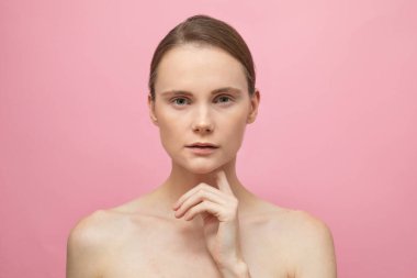 Güzel, şehvetli, üstsüz esmer kadın pembe arka planda yalnız duruyor, poz veriyor. Mutlu kadın model. İnsani duygular ve duygular. Çıplak makyaj. Spa