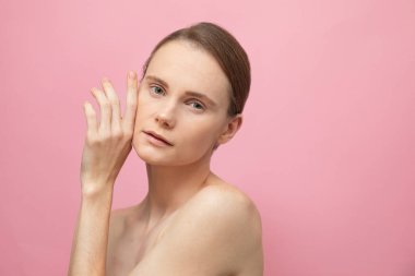 Güzel, şehvetli, üstsüz esmer kadın pembe arka planda yalnız duruyor, poz veriyor. Mutlu kadın model. İnsani duygular ve duygular. Çıplak makyaj. Spa