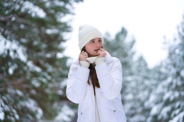 Kışın açık havada gülümseyen güzel bir genç kadın. Kış konsepti Beyaz elbiseler, kar, orman, soğuk hava, donmuş