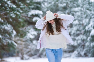 Kışın açık havada gülümseyen güzel bir genç kadın. Kış konsepti Beyaz elbiseler, kar, orman, soğuk hava, donmuş