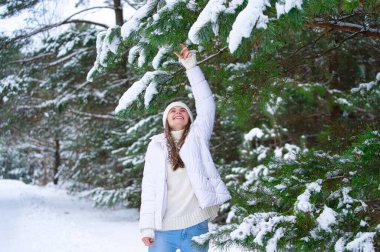Kışın açık havada gülümseyen güzel bir genç kadın. Kış konsepti Beyaz elbiseler, kar, orman, soğuk hava, donmuş