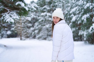 Kışın açık havada gülümseyen güzel bir genç kadın. Kış konsepti Beyaz elbiseler, kar, orman, soğuk hava, donmuş