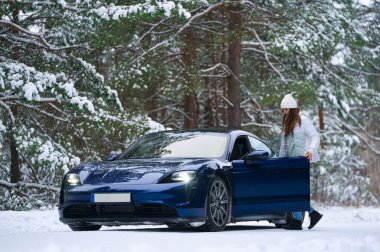 Kışın açık havada gülümseyen güzel genç bir kadın arabaya biniyor. Kış konsepti