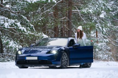 Kışın açık havada gülümseyen güzel genç bir kadın arabaya biniyor. Kış konsepti