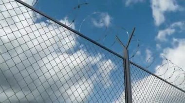 Barbed wire chain link fence against skyline timelapse at the restricted area
