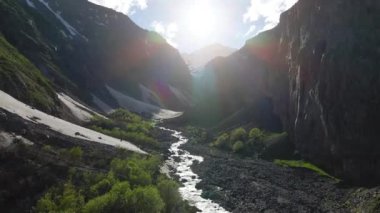 Arka planda kar zirvesi olan dağ kanyonunda uçan hava aracı.
