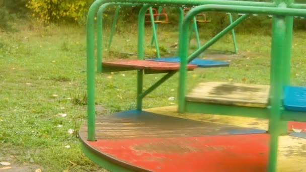 Rotation of a roundabout in the rain on the playground close-up — Stock Video