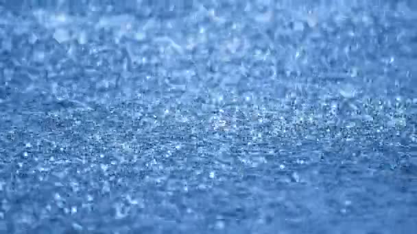 Gocce di pioggia in tempo reale che cadono sull'acqua blu, DOF — Video Stock