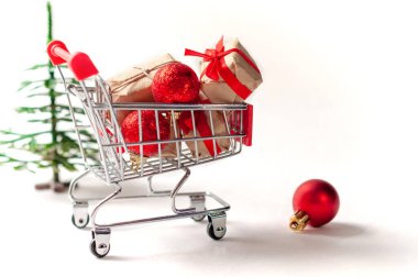 Hediyeler ve Noel süsleri beyaz arka planda bir el arabasında. Noel satışları konsepti, indirimler..