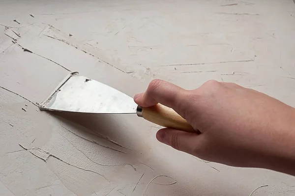 El spatulayı tutar ve macunu uygular. Yeniden yapılanma ve onarım süreci.