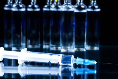 Siyah arkaplanda ampul ve şırınga.