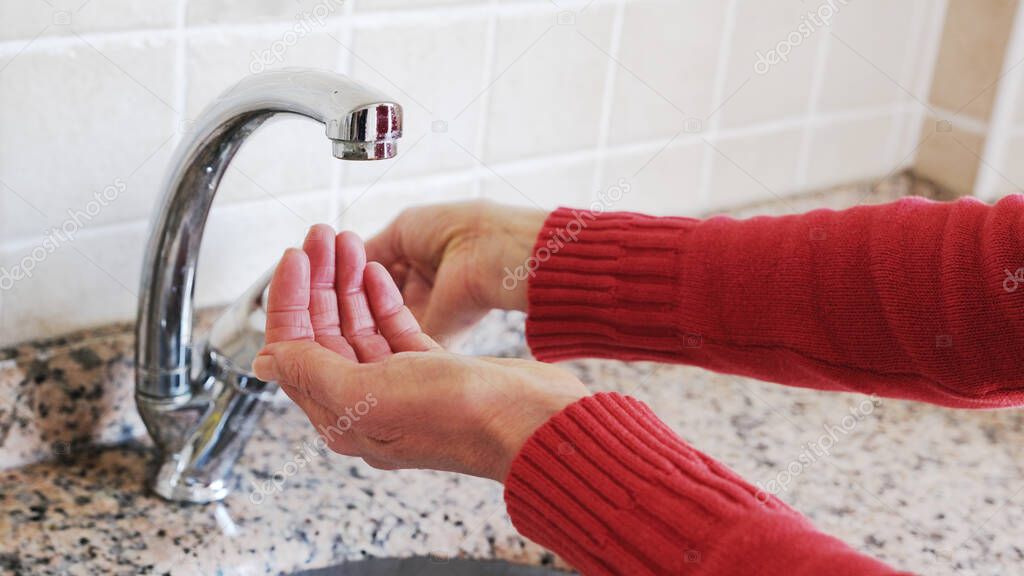 woman's hands opening the fountain.red sweater woman's sleeves and water shortage.