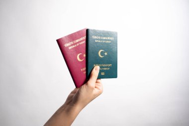Beyaz arka planda iki Türk pasaportu olan bir kadın. Kırmızı Türk pasaportu ve yeşil Türk pasaportu..