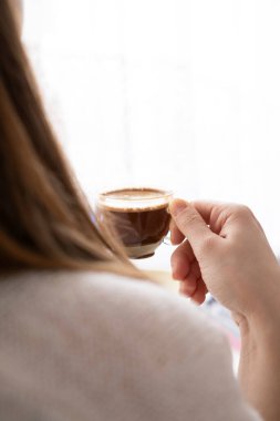 Pencerenin kenarında kahve içen genç bir kadın. Sabahları Türk kahvesi içen bir kadın..