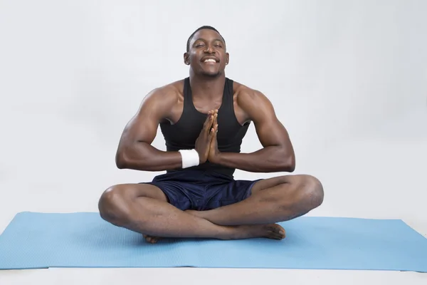Jovem desportista sorrindo medita no tapete — Fotografia de Stock