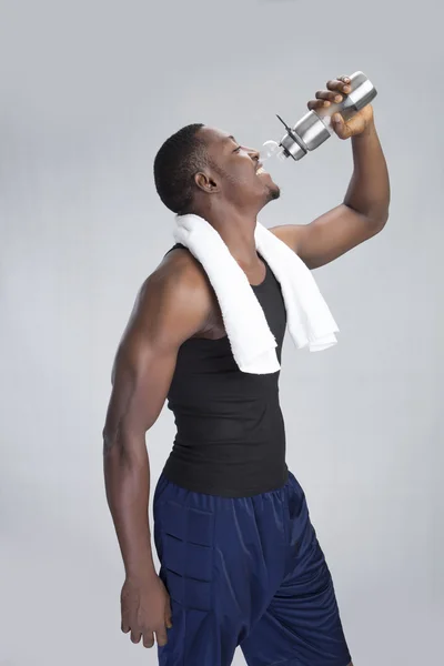 Young sportsman with towel drinking water — Stock Photo, Image