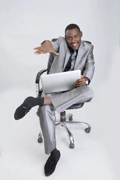 Young businessman with laptop smiling and gesturing — Stock Photo, Image