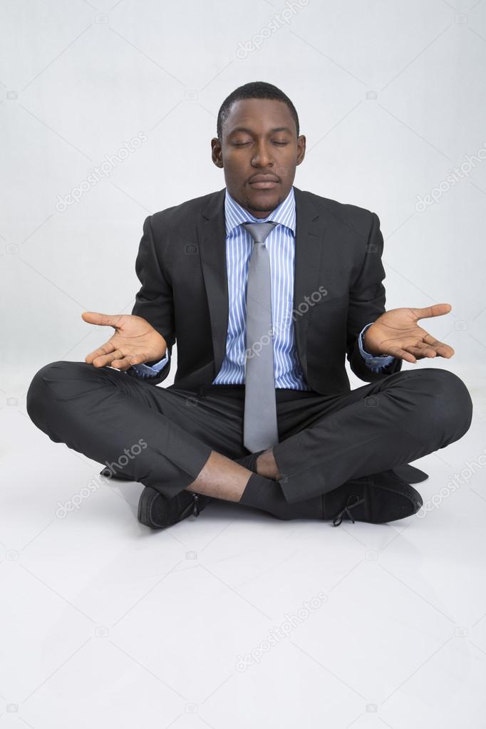 Young businessman sitting on floor and meditates