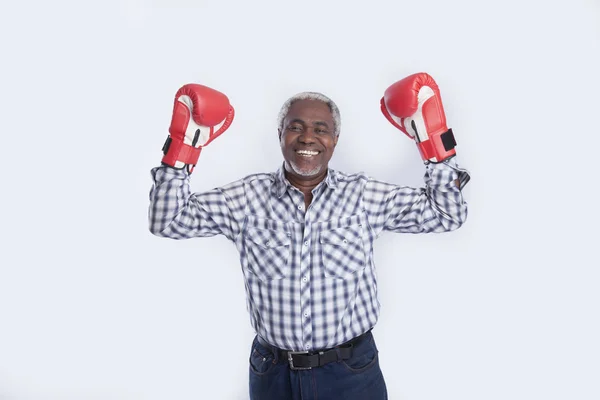 Leeftijd man met bokshandschoenen op grijs — Stockfoto