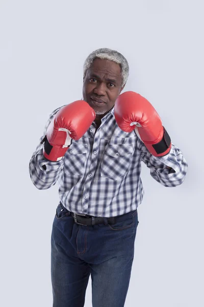 Alter Mann mit Boxhandschuhen auf grau — Stockfoto