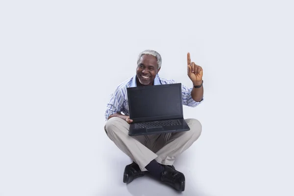 У віці чоловік з ноутбуком на сірому — стокове фото
