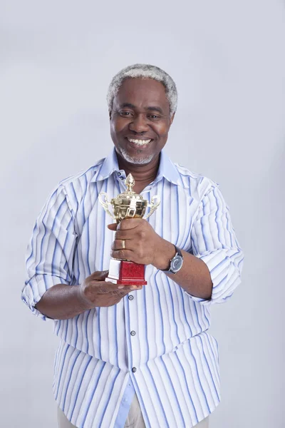 Un homme âgé tient la coupe des gagnants — Photo