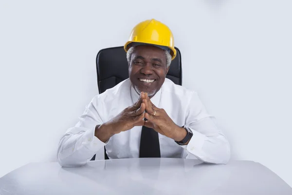 Leeftijd zakenman in helm zit en glimlacht — Stockfoto