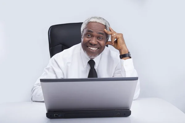 Empresário envelhecido olha sorrindo para laptop — Fotografia de Stock