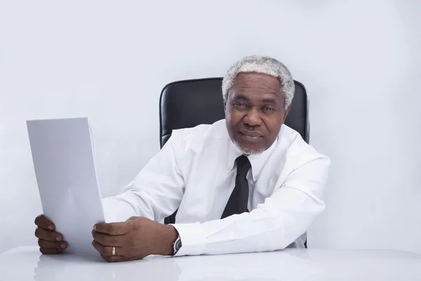 Homme d'affaires âgé assis sur un fauteuil avec des papiers — Photo