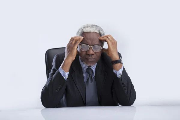 Пожилой бизнесмен в очках возле кресла — стоковое фото