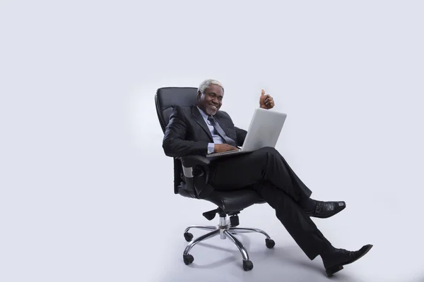 Homem de negócios envelhecido senta-se na poltrona com laptop — Fotografia de Stock